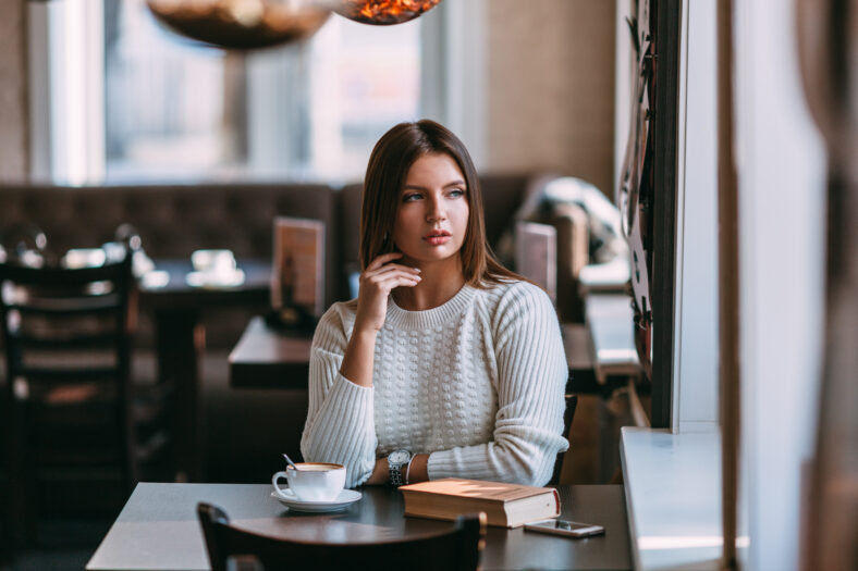 pretty young woman sitting in the cafe with a cup of coffee