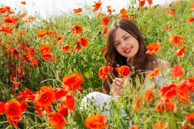 Girl walks in a field of poppies