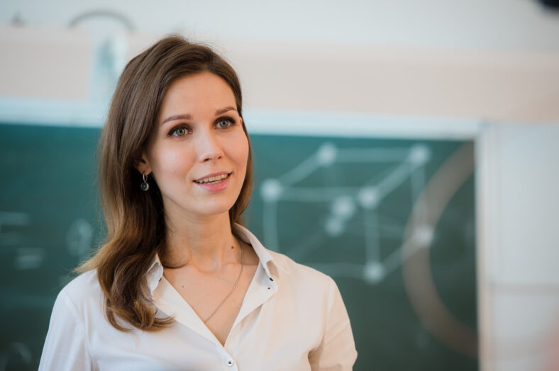 Portrait of happy teacher standing in front of black board.