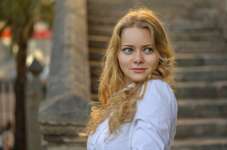 beautiful blond woman in white posing, stairs on the background .