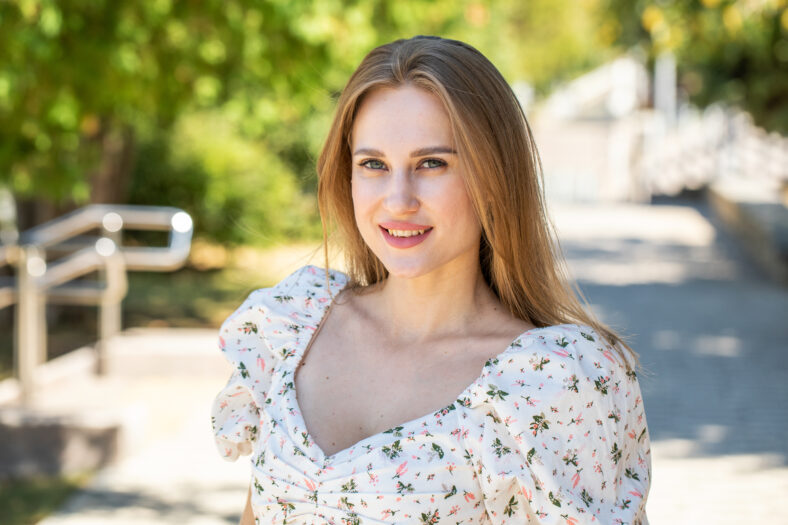Portrait of a young beautiful blonde girl in a white summer dress