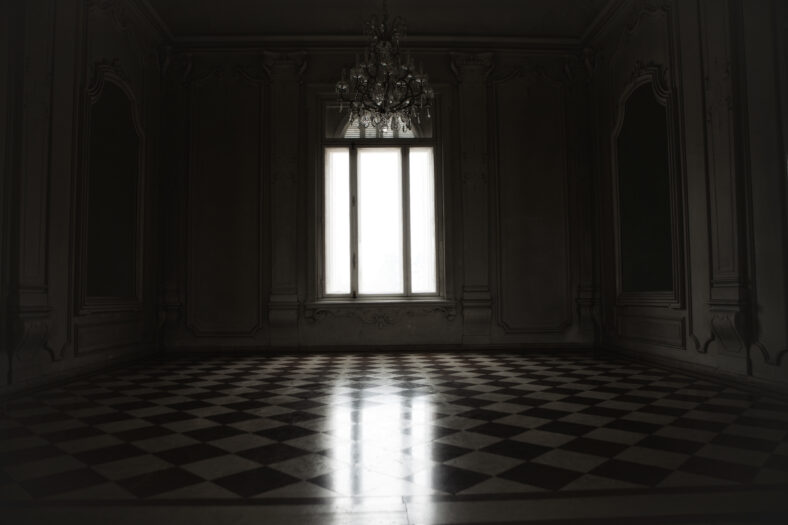 Window lit with mysterious white light in a spooky room built in baroque style.