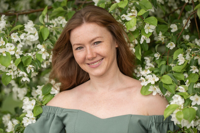 Young red-haired woman posing in a blooming garden