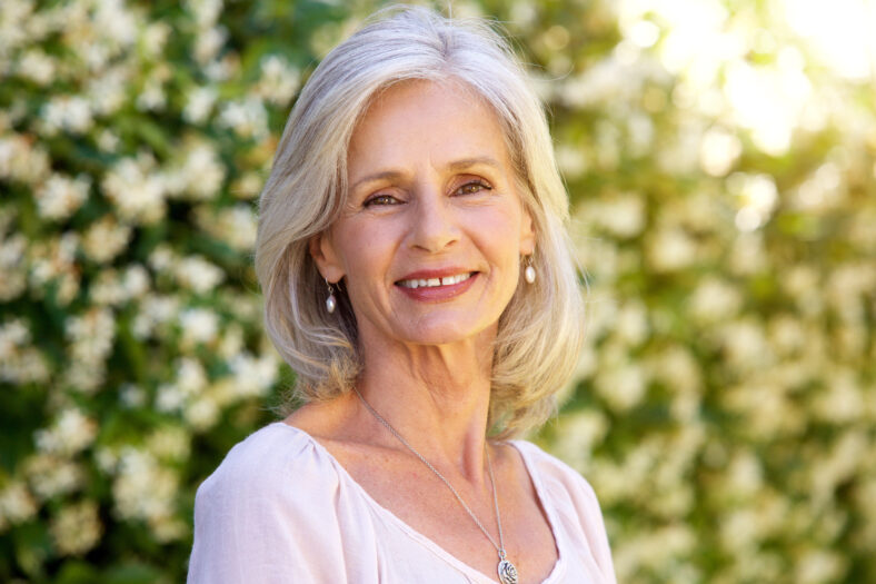 Close up portrait of happy older woman standing outside in summer