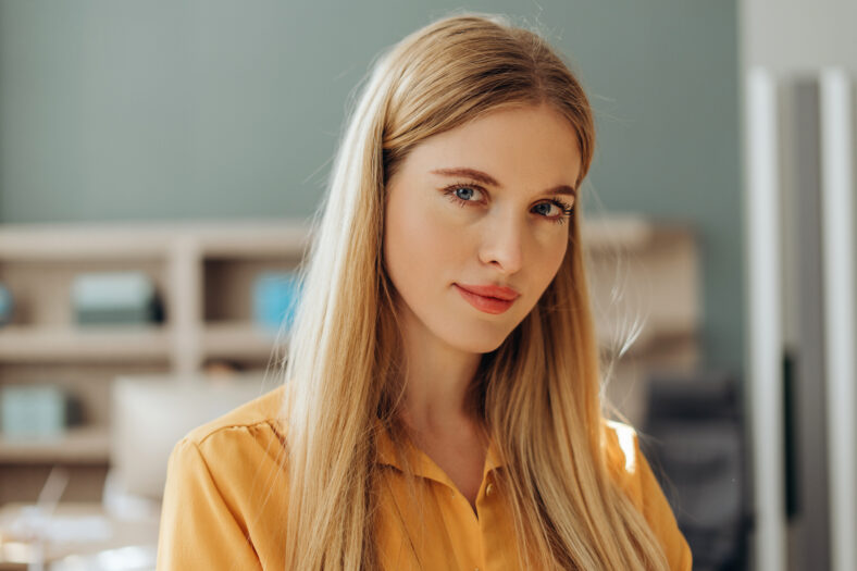Confident young blonde businesswoman posing in her modern office, looking serene and professional