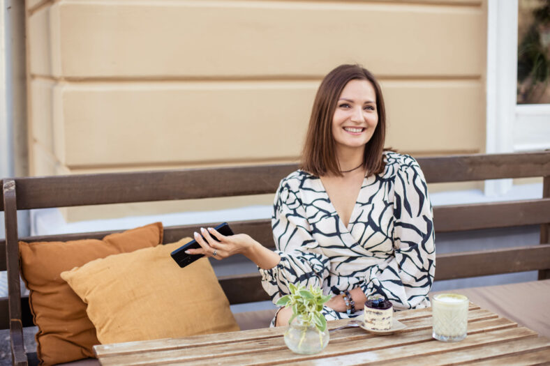 Young woman in summer cafe, sunny day in modern city, close up.