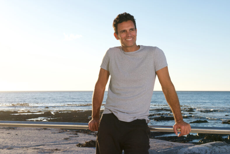 Portrait of handsome middle age man smiling by sea