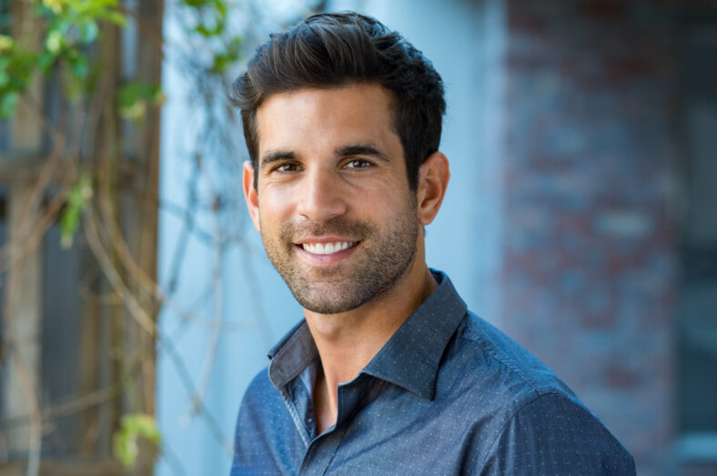 Handsome mid adult man smiling and looking at camera. Portrait of happy young casual man. Close up portrait of hispanic guy standing outdoor.