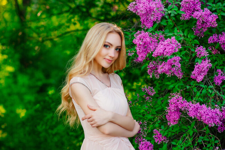 charming beautiful blonde girl, portrait of girl surrounded by blooming flowers , beautiful smile, girl in spring garden
