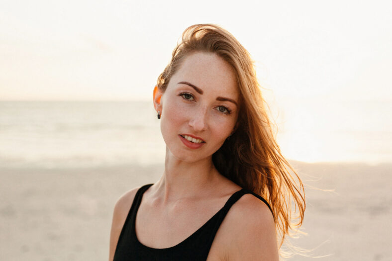 Retrato de una mujer atractiva mirando a la cámara en Ocean Beach durante el atardecer
