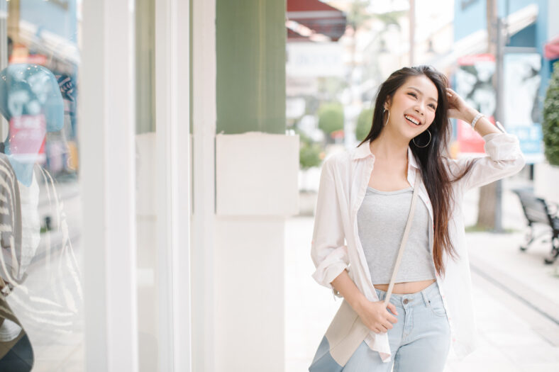 Summer sunny lifestyle fashion portrait of young stylish hipster Asia woman walking on the street, wearing cute trendy outfit