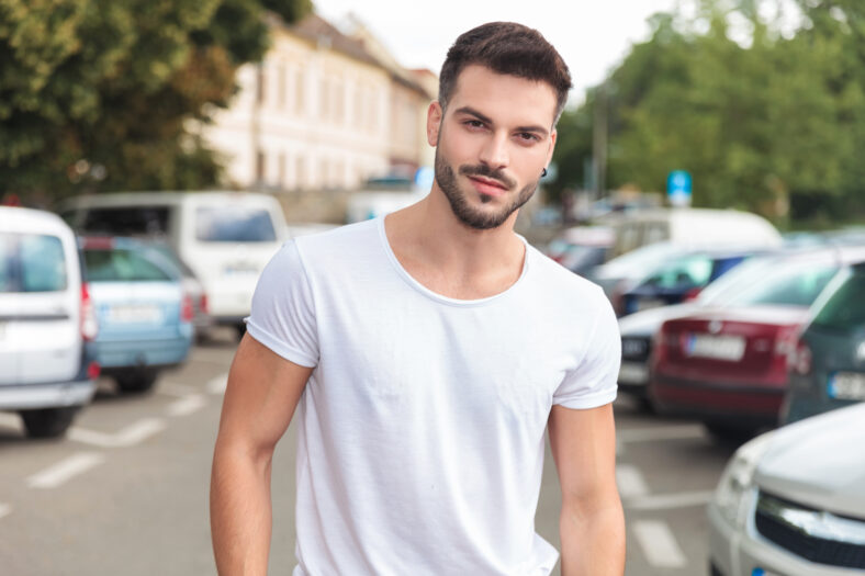 portrait of young casual man with ring in ear standing in a street in a city, outdoor picture