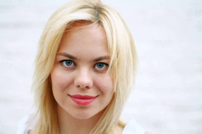 face of pretty blonde against white wall
