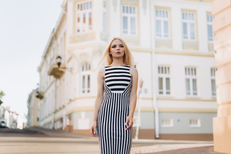Street portrait of young beautiful blodie caucasian stylish girl walking along the streets in summer warm day