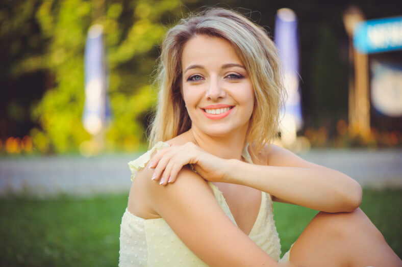 Chica de belleza con una suave sonrisa romántica sobre el fondo del parque de verano. Hermosa mujer joven feliz descansando, colores pastel - imagen