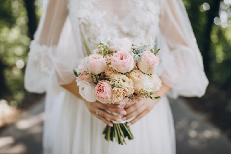 bride in a white wedding dress holding a bouquet of roses, peonies and greenery