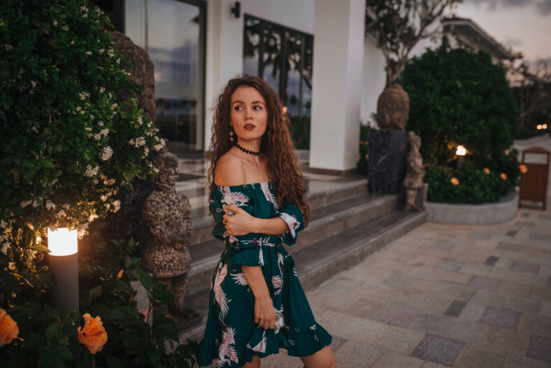 girl at sunset on the waterfront with palm trees in a green dress