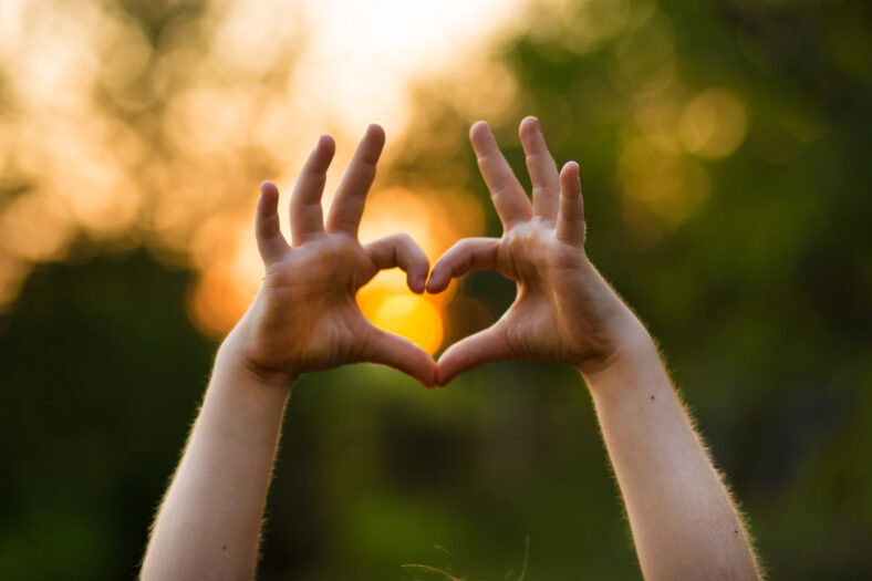 Heart shape hand of kid's body language for children's love, kindness, love concept. Heart Hand on nature sunset bokeh background