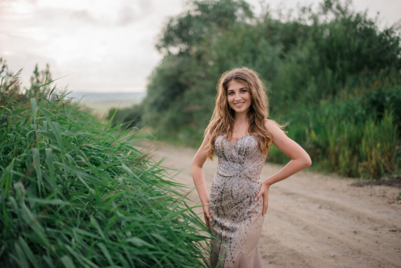 beautiful young girl in a summer dress in a field on a background of green grass