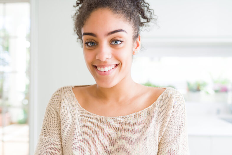 Beautiful young african american woman with afro hair with a happy and cool smile on face. Lucky person.
