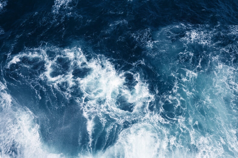 Top view on blue ocean waves and foam.