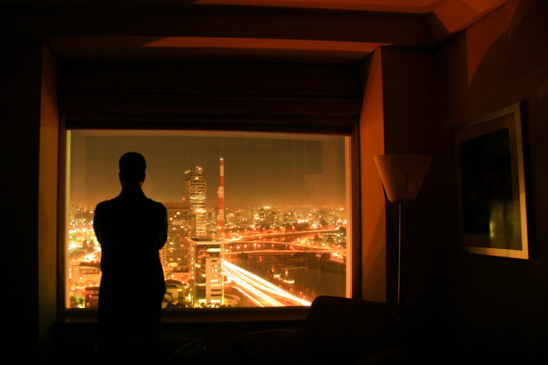 Silhouete of a person against the night landscape of the city of Sao Paulo, in a hotel room, in Brazil