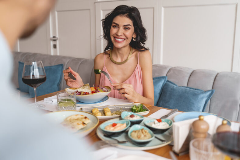 Attractive lady looking at man and smiling while sitting at the table with delicious food