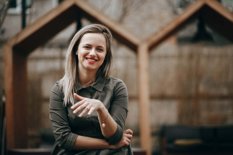 Beautiful young girl posing in the yard on the brick wall background.