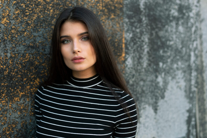 Closeup portrait of a sensual girl with straight brown hair and green eyes looking at camera.