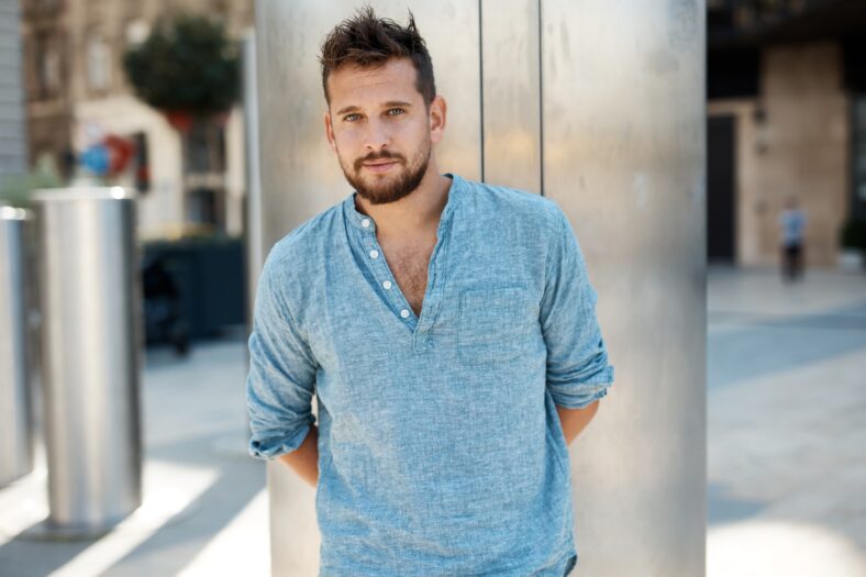 Handsome man outdoor standing on city street waiting.