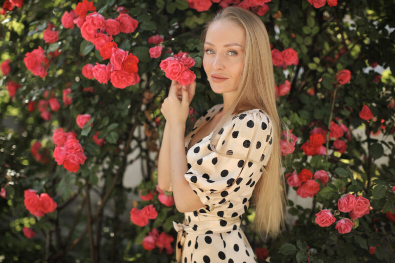 Portrait of a young woman in roses flowers outdoor. High quality photo