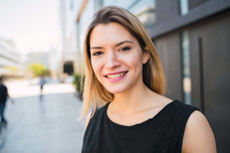 Portrait of young business woman standing outside office buildings. Business and success concept.