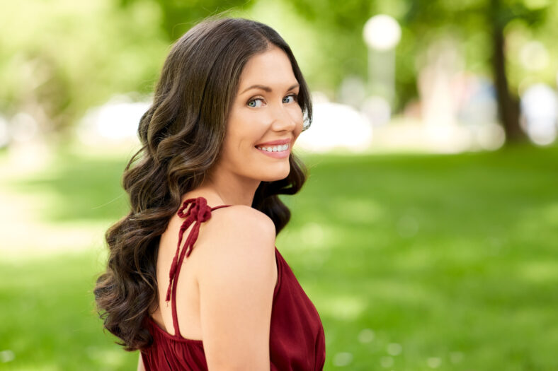 leisure and people concept - portrait of happy smiling woman with long wavy hair at summer park