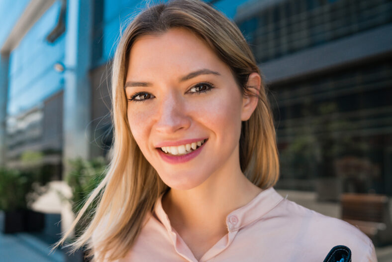 Retrato de joven mujer de negocios parada fuera de los edificios de oficinas. Concepto de negocio y éxito.