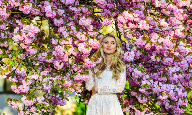 Spring holidays. real female beauty. summer weather and nature. woman with long hair in park. pink cherry tree blossom. beautiful woman in dress. girl with blooming sakura tree. spring fashion style.
