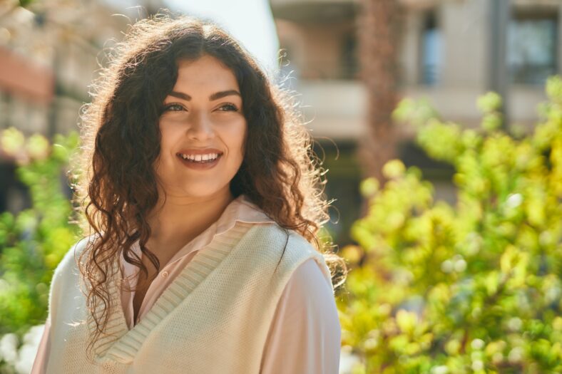 Young hispanic woman smiling happy standing at the city.