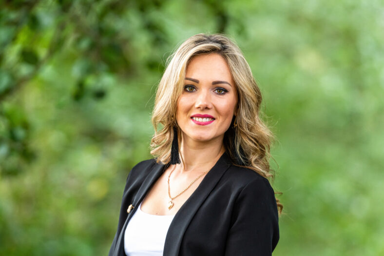 portrait of beautiful blond smiling woman in forest, green leaves on background