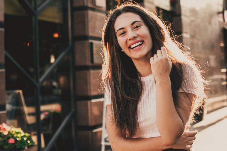 Beautiful smiling woman walking in the city on summer day.