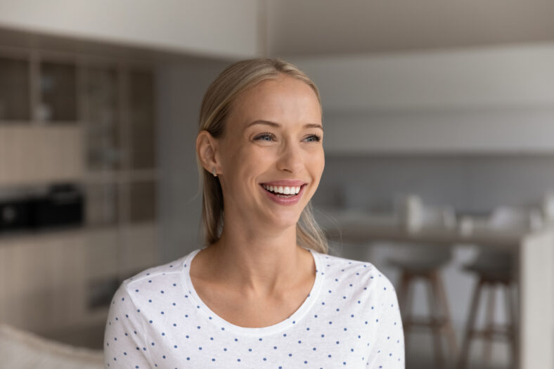 Happy beautiful 30s blonde woman home head shot portrait. Cheerful positive female homeowner in casual enjoying being in new apartment, looking away with toothy smile, laughing, thinking of future,