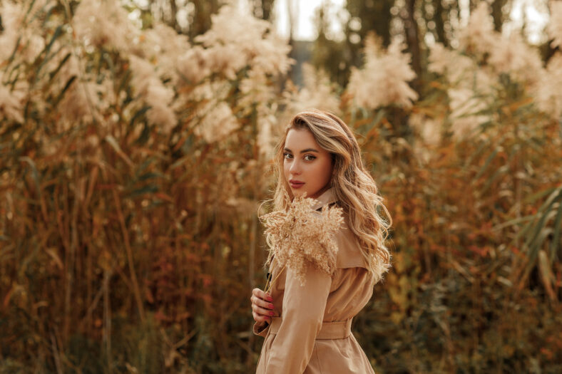 Beautiful girl in white dress running on the autumn field of wheat at sunset time.