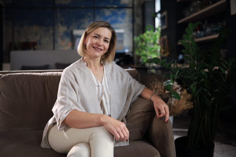 Beautiful blond middle aged woman relaxing sitting on sofa.