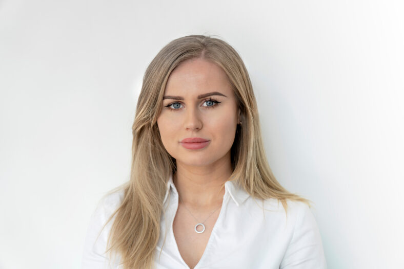 Blonde woman in white blouse. Smiling, confident, content, happy, pretty.