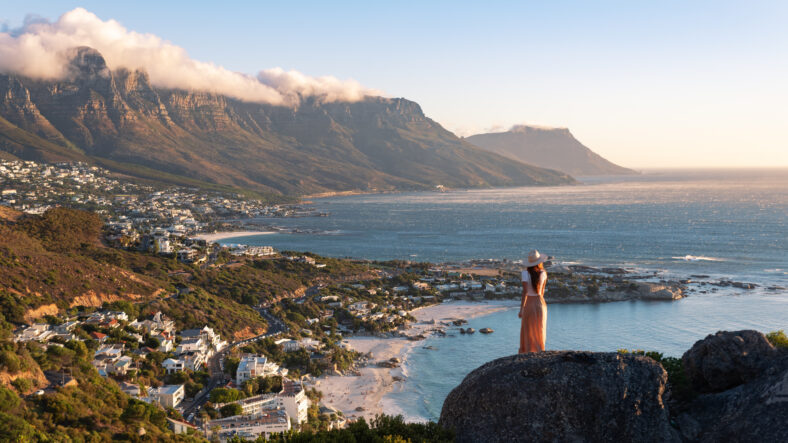 Young pretty woman watching the sunset. Tourist in Cape Town. Travel blogger watching sunset in Camp's Bay, Cape Town, South Africa.
