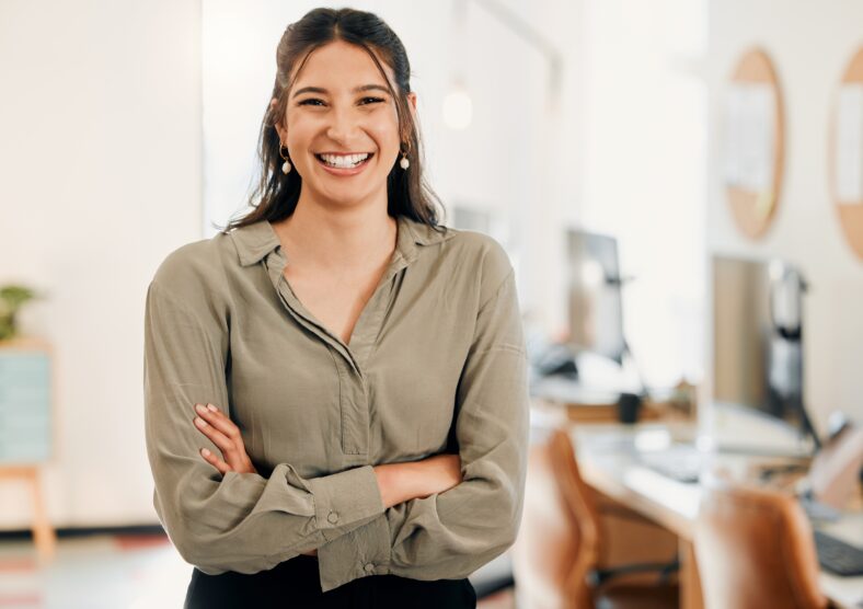 Shot of an attractive young businesswoman standing alone in the office with her arms folded.
