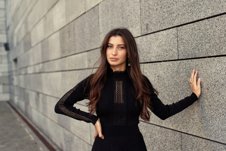 young woman leaning against a stone wall