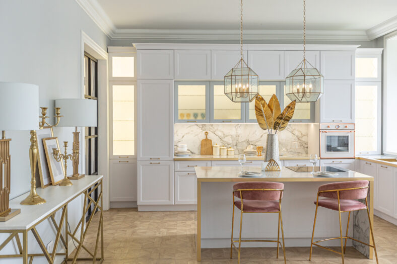 a close view of the white stylish kitchen with a cooking island in the luxurious interior of a modern apartment in light colors with stylish furniture.