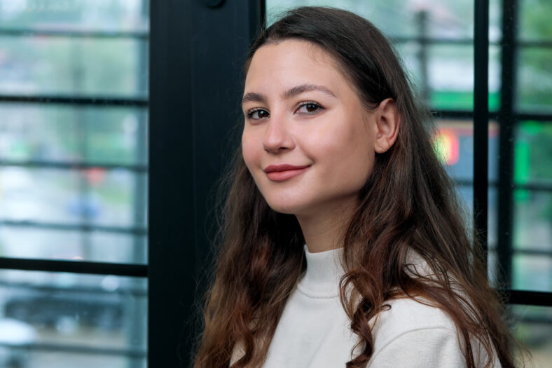 Retrato de una joven hermosa y hermosa con el pelo largo y ondulado en un suéter blanco