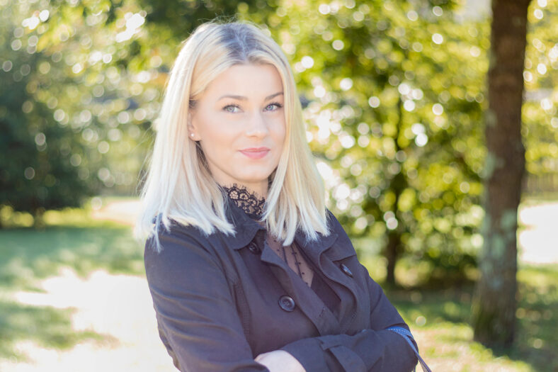 pretty smiling blonde woman looking at camera in a park
