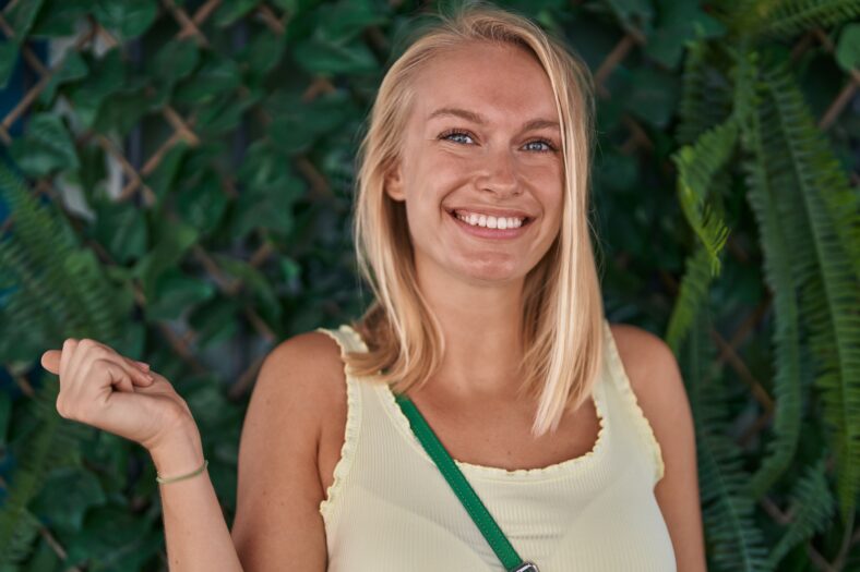 Young caucasian woman standing outdoors screaming proud, celebrating victory and success very excited with raised arm