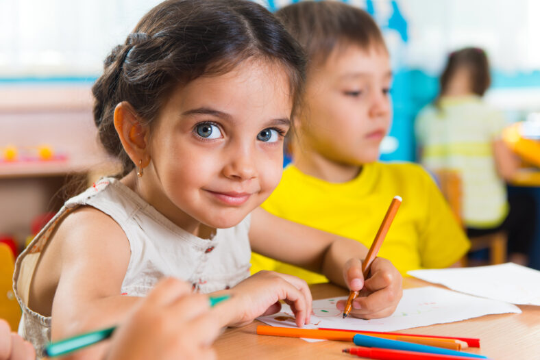 Group of cute little preschool kids drawing with colorful pencils